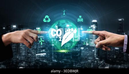 Digital representation of carbon footprint reduction concept showing futuristic city skyline and sustainability icons with human hands pointing at Stock Photo
