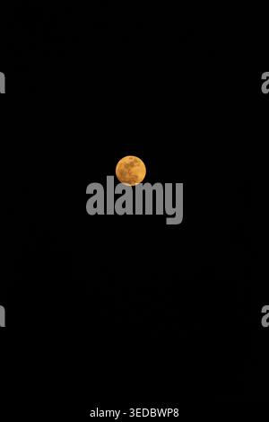 Buddha Purnima Bright orange full moon centered against a deep black night sky Stock Photo