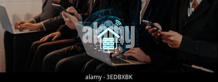 Business professionals use mobile devices and laptops at a networking event, highlighting themes of digital connectivity and home automation Stock Photo