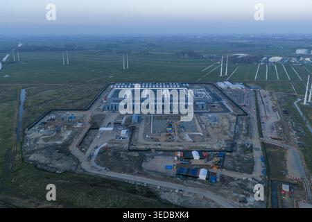 Aerial view of a hyperscale data center facility under construction surrounded by green fields and wind turbines in Netherlands. Stock Photo