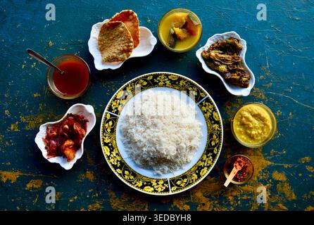 Sri Lankan rice and curry meal with deviled chicken and side dishes served on rustic blue table, Midigama, Sri Lanka Stock Photo