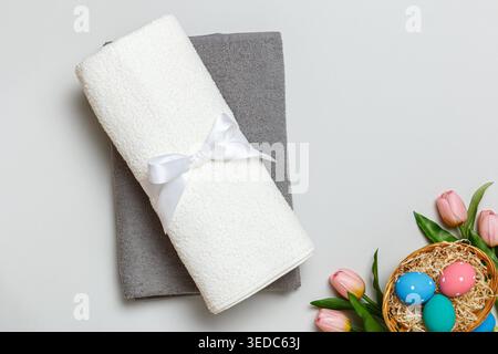 Top view of a stack of white and gray towels and an Easter basket full of eggs. Stock Photo