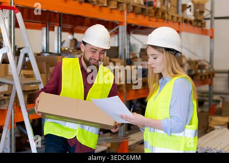 Male warehouse employee presenting package to female colleague taking notes on clipboard. Order processing and inventory accuracy in modern distribution facility Stock Photo
