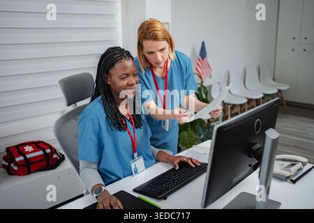 Two female nurses discussing patient information at a computer workstation Stock Photo