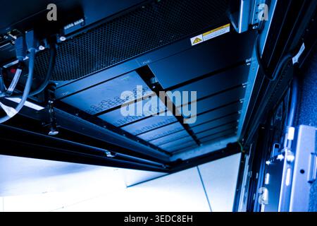 An upward view of a sophisticated data center rack showcasing high-tech servers and intricate cable arrangements, reflecting modern IT infrastructure. Stock Photo