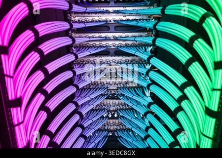 Close-up view of vibrant fiber optic cables arranged in a server rack, showcasing colorful illumination and modern technology in data communication. Stock Photo