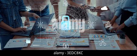 A dynamic team in a modern office setting collaborates on projects with laptops and documents, emphasizing cybersecurity and data protection in their Stock Photo