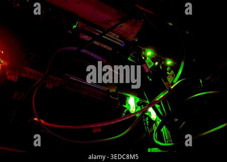 A captivating view of illuminated circuitry and wires engulfed in darkness. Neon green and red lights create an abstract technological aesthetic, evok Stock Photo