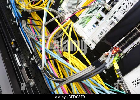 A close-up view of colorful network cables connecting various devices in a server rack, showcasing the complexity and vibrancy of modern data infrastr Stock Photo