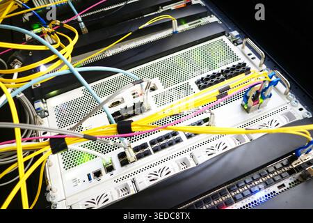 This image showcases a data center with numerous cables connecting servers. The vibrant cables illustrate the complexity of modern network systems, em Stock Photo