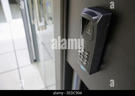 A close-up view of a modern fingerprint scanner mounted on a wall, showcasing its sleek design and security features, ideal for access control in buil Stock Photo