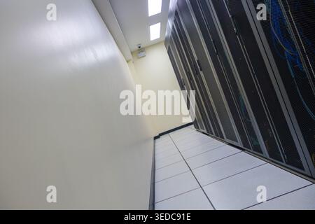 A well-organized corridor in a data center featuring server racks, informative network cables, and efficient lighting, ideal for technology-focused pr Stock Photo