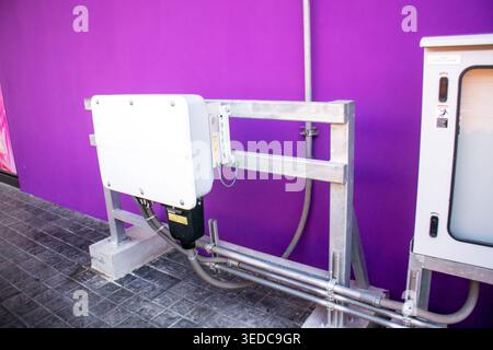 This image shows equipment mounted on a vibrant purple wall, highlighting modern technology in an urban setting. It features unique colors and industr Stock Photo