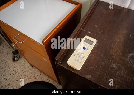 A close-up view of a remote control placed on a wooden table next to a stylish cabinet, capturing a modern office workspace atmosphere. Stock Photo