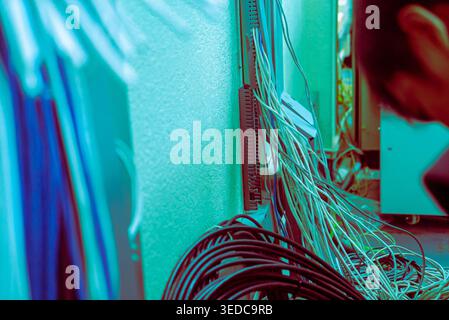 A technician works on network cables in a server room, showcasing the intricate setup of data infrastructure and technology management. Stock Photo