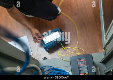 A technician is performing testing on network equipment, carefully connecting cables to ensure proper functionality in a professional office environme Stock Photo
