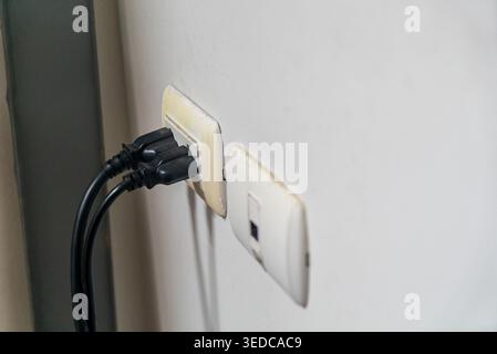 A close-up view of an electrical wall socket featuring two connected plugs. The image highlights the essential role of power outlets in modern homes a Stock Photo