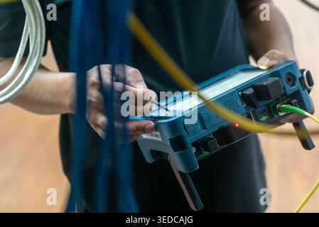A technician conducts electrical testing using advanced equipment, demonstrating precision and professionalism in a work environment with numerous cab Stock Photo