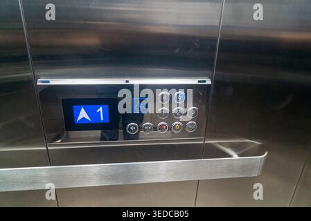 Close-up of an elevator control panel featuring numeric buttons and an indicator screen, showcasing modern design and user-friendly access for all bui Stock Photo