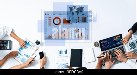 A diverse team working together in a modern office analyzing data through graphs and charts, using laptops and tablets for effective collaboration Stock Photo