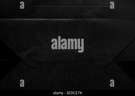 Abstract black paper texture with geometric folds and grunge effect. Dark minimal cardboard background with visible creases and textured surface patte Stock Photo