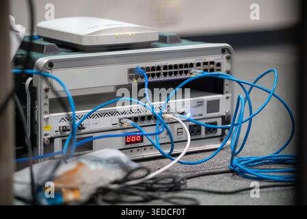 A detailed view of networking equipment showcasing a router, switch, and connected cables on a workspace. Ideal for technology and data management the Stock Photo