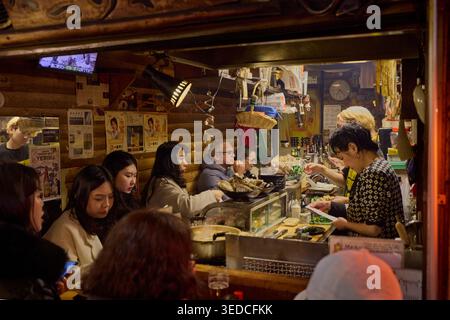 People sitting at the bar in a small izakaya at Omoide Yokocho, or Memory Lane, a nostalgic bar district in Shinjuku City, Tokyo, Japan. Stock Photo