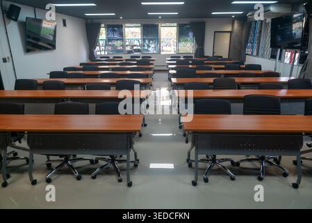 This image showcases a spacious modern conference room designed for professional meetings and seminars. The empty layout features rows of tables and c Stock Photo