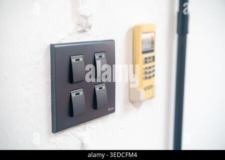 A modern wall light switch control panel featured alongside a yellow remote device, showcasing a clean and minimalist interior design aesthetic. Stock Photo