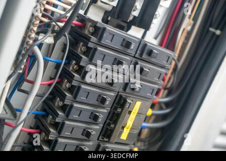 Close-up of an electric circuit breaker panel showcasing various circuit breakers, wiring, and connections essential for electrical safety and power m Stock Photo