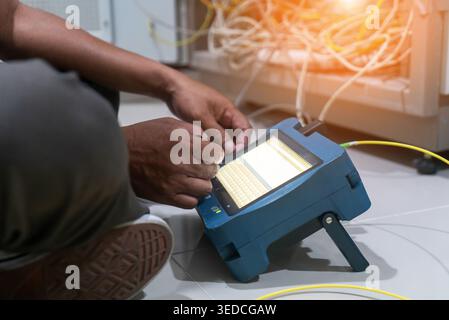 A technician uses a network tester device to check connections in a data center. The scene highlights the importance of maintaining network performanc Stock Photo