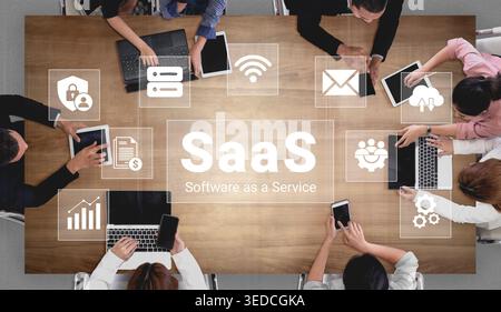 A diverse group of business professionals is collaborating on a Software as a Service (SaaS) project. Laptops and tablets are used to enhance teamwork Stock Photo