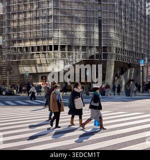People cross the street at a pedestrian crossing on a sunny winter day. Ginza, Chuo City, Tokyo, Japan. Stock Photo