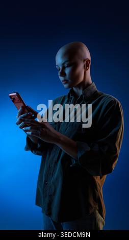 Thoughtful woman browsing smartphone under blue studio light Stock Photo