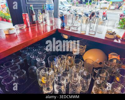 clean beer mugs and glassware is organized on a lower shelf behind the counter, ready for service, bar desk, Vietnam Stock Photo