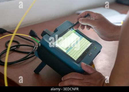 A technician using a portable handheld device to analyze data and monitor systems within a workspace. This modern technology enhances efficiency and p Stock Photo