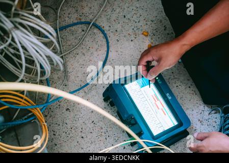 A technician inspects a testing device on the floor while working with cables. This image captures the essence of technology and maintenance in a prof Stock Photo