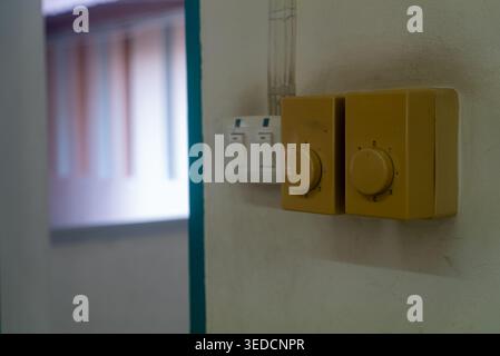Close-up of a yellow light switch and dimmer on a wall in an interior setting, showcasing elements of modern residential decor and functionality in li Stock Photo