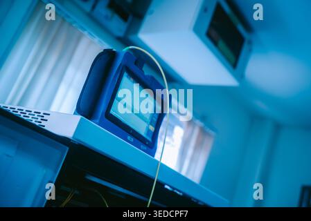 A close-up view of a medical monitor in blue light, displaying data and measurements. The modern workspace highlights diagnostic tools in a clinical s Stock Photo