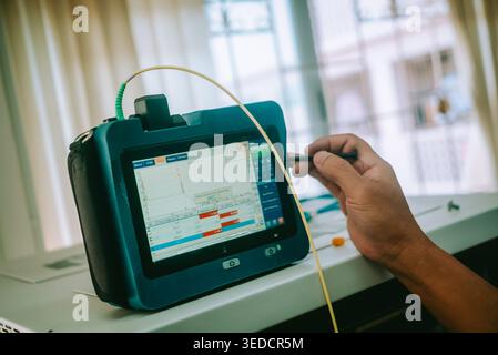 A close-up view of a modern handheld device used for data analysis in a professional setting. The screen displays analytical data as a person conducts Stock Photo