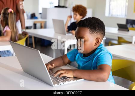 Diverse elementary students using laptops at school African American boy typing on silver laptop Stock Photo