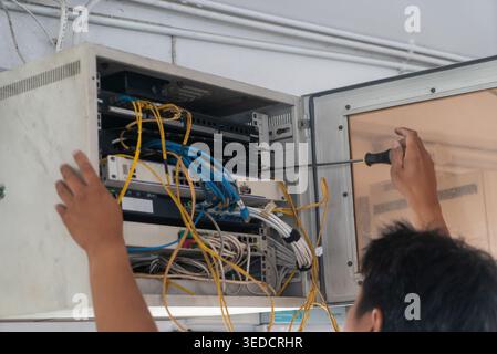 A technician performing maintenance on a server cabinet, managing cables and connections. The image showcases hands at work with tools in a tech envir Stock Photo
