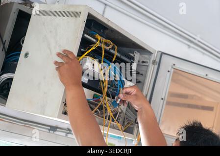 A technician performs critical network maintenance, managing cables and connections in an organized workspace. The image captures the importance of pr Stock Photo