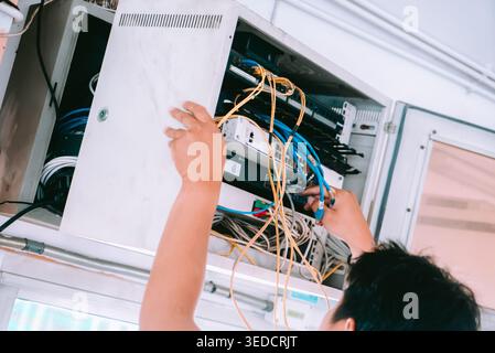A technician organizes cables inside a cabinet, showcasing the importance of efficient wire management in a professional workspace. Stock Photo