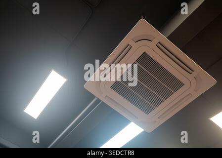 This image showcases a ceiling-mounted air conditioner in a modern office setting, highlighting its sleek design and efficient cooling capability. Stock Photo