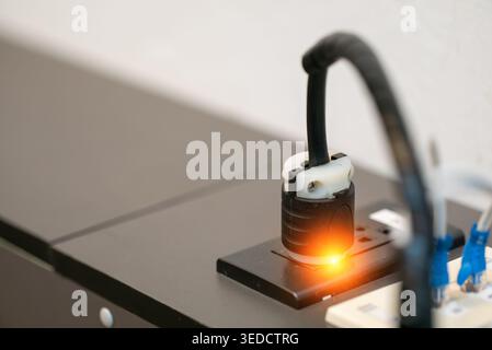A close-up view of an electrical plug connected to a socket, showcasing an illuminated switch. This image highlights modern electrical technology and Stock Photo