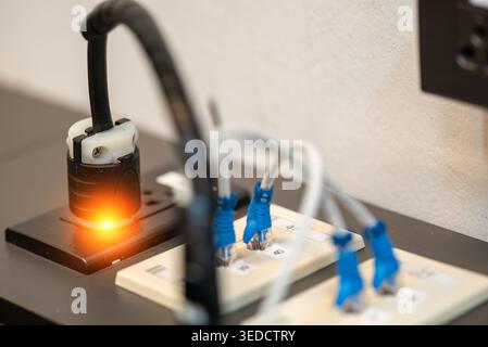 A close-up view of an electric power socket featuring connected cables and an indicator light, showcasing modern electrical installation in a workspac Stock Photo
