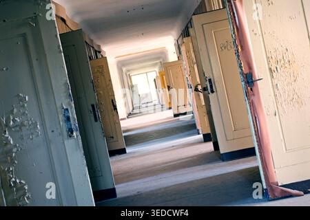 An abandoned, long hallway with countless old doors in a dilapidated building Stock Photo