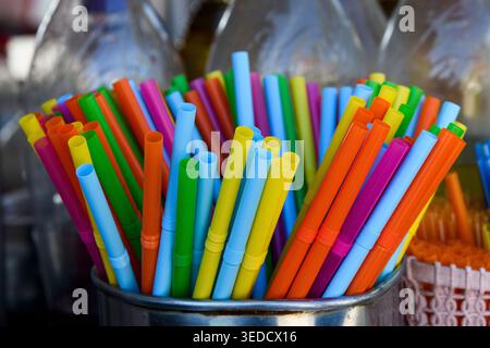 Multi-colored, plastic, disposable drinking straws with bellows standing upright in a shiny, silver metal container. Stock Photo