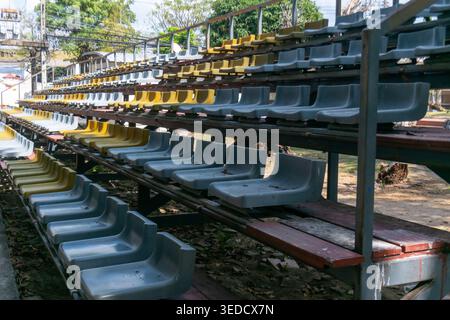 A series of empty stadium seats arranged in neat rows at an outdoor venue, showcasing a blend of yellow and gray colors under natural sunlight. Stock Photo